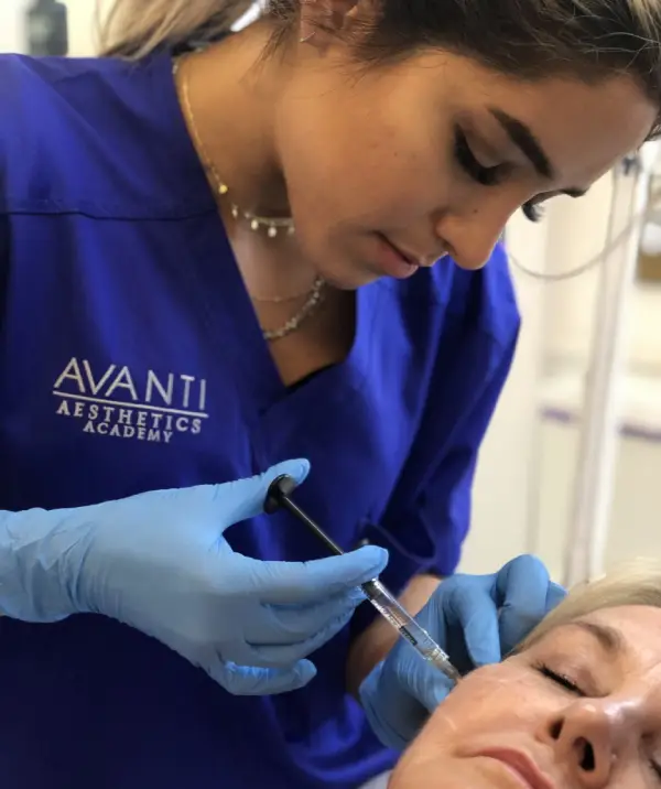 A medical professional injecting a models cheek area with dermal filler during a training session at Avanti Aesthetics Academy