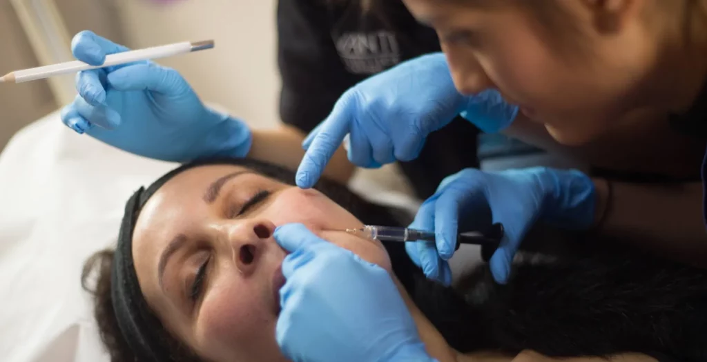 A doctor performing a nasolabial fold injection under 1:1 trainer guidance during foundation aesthetics training at Avanti Aesthetics Academy